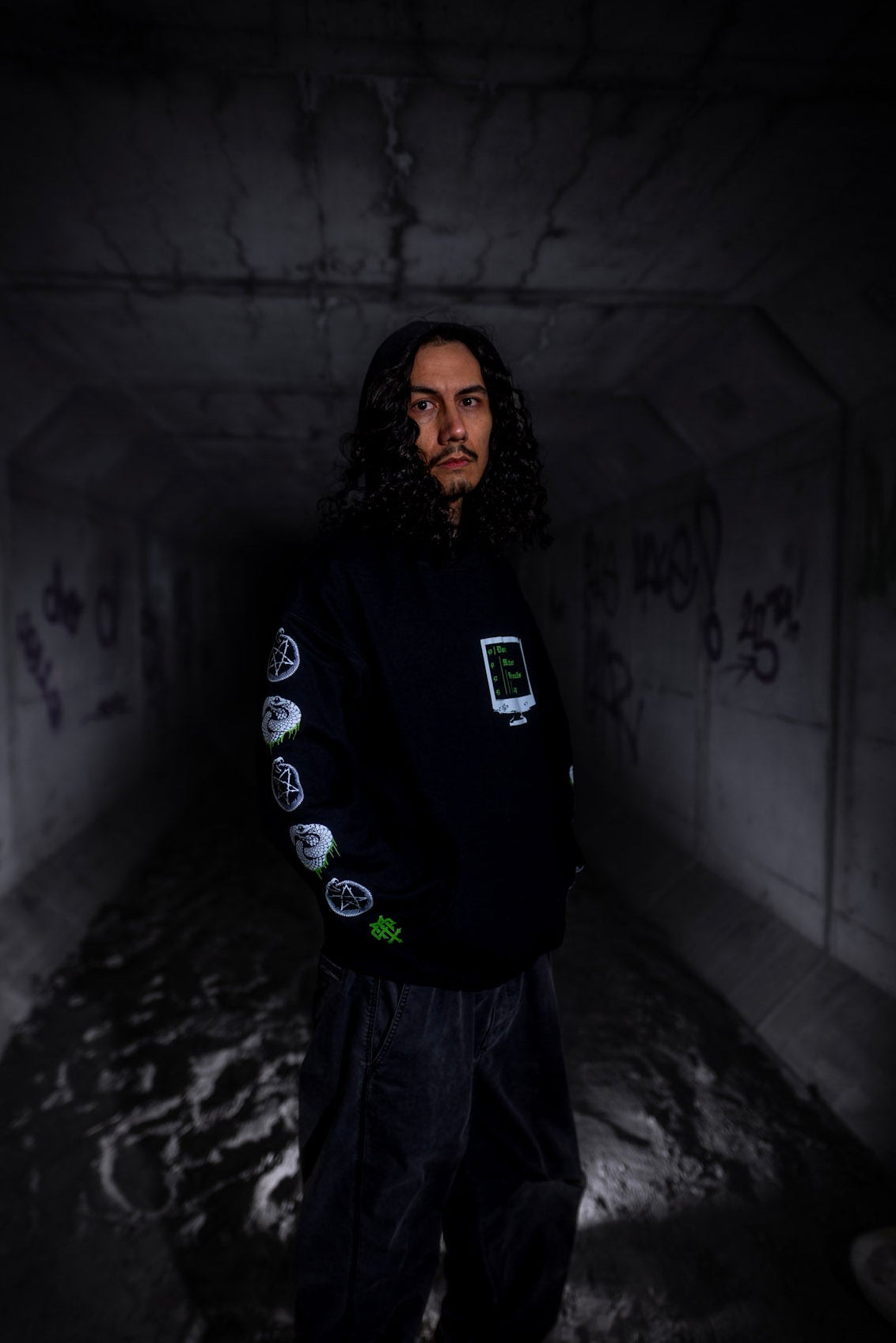Male model front view wearing the Dark Matter Threads Knowledge unisex hoodie in black, featuring front and sleeve graphic artwork.