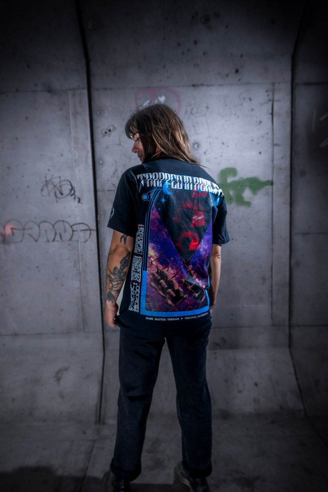 Female model back view wearing the Dark Matter Threads Trapped in Reality unisex t-shirt in black, featuring the back graphic, 100% cotton.