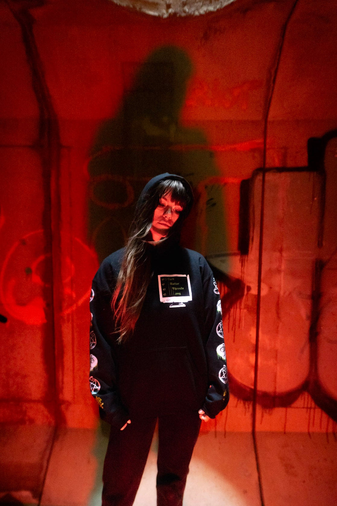 Female model front view wearing the Dark Matter Threads Knowledge unisex hoodie in black, featuring front graphic artwork.