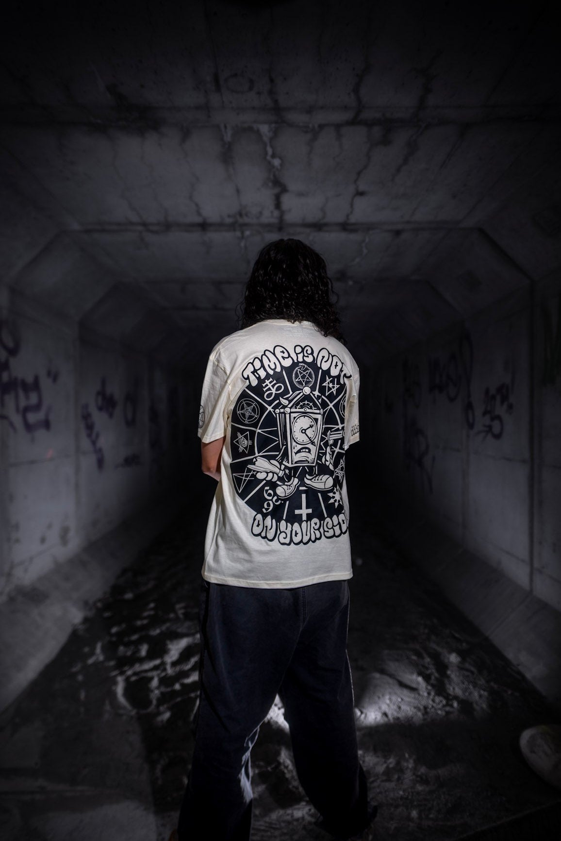 Male model back view wearing the Dark Matter Threads Time unisex 100% cotton t-shirt with artwork graphic print.