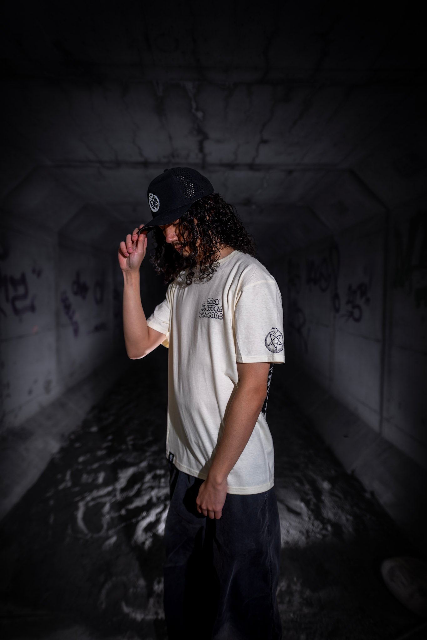 Male model front-side view wearing the Dark Matter Threads Time unisex 100% cotton t-shirt with graphic front and sleeve design.